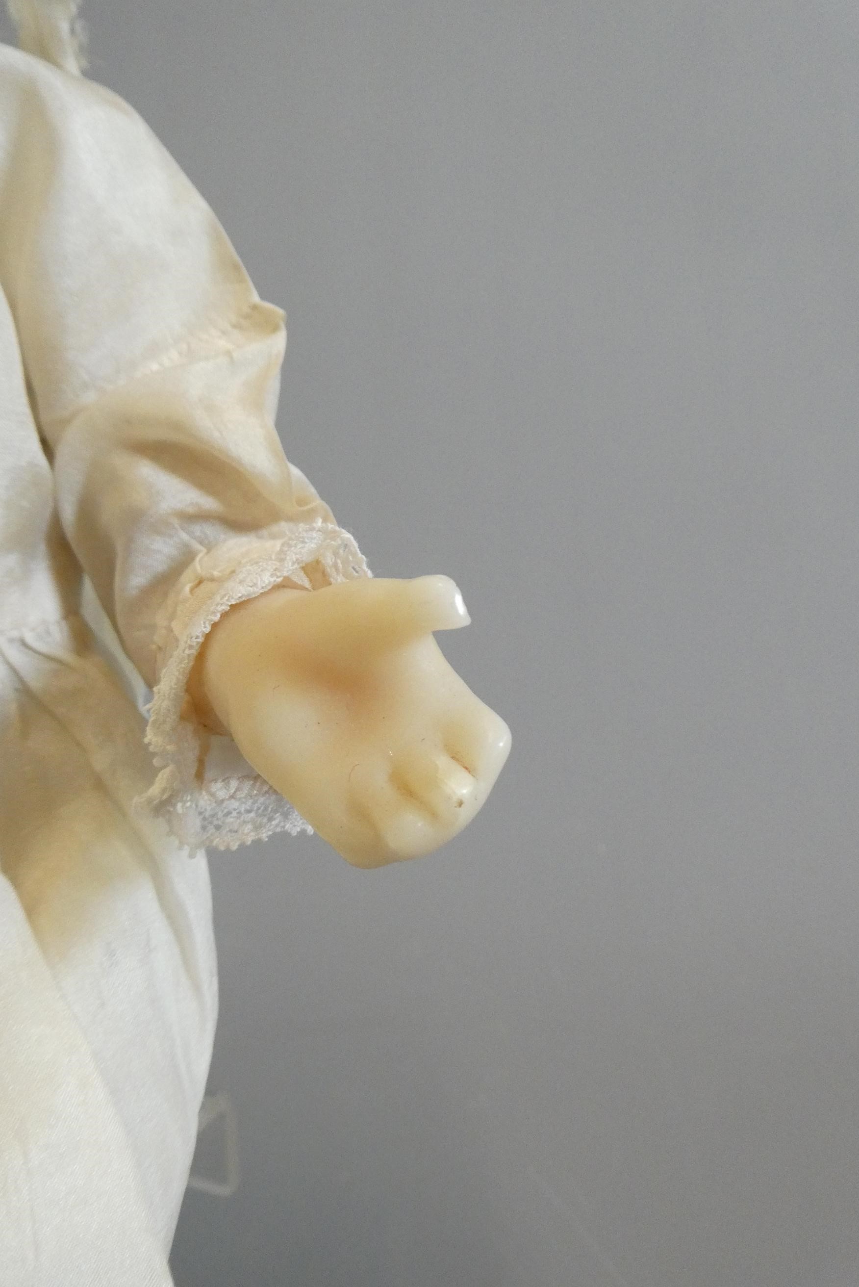 A seated wax shoulder head doll, with blue glass fixed eyes, open mouth, teeth, blond wig, fabric Image