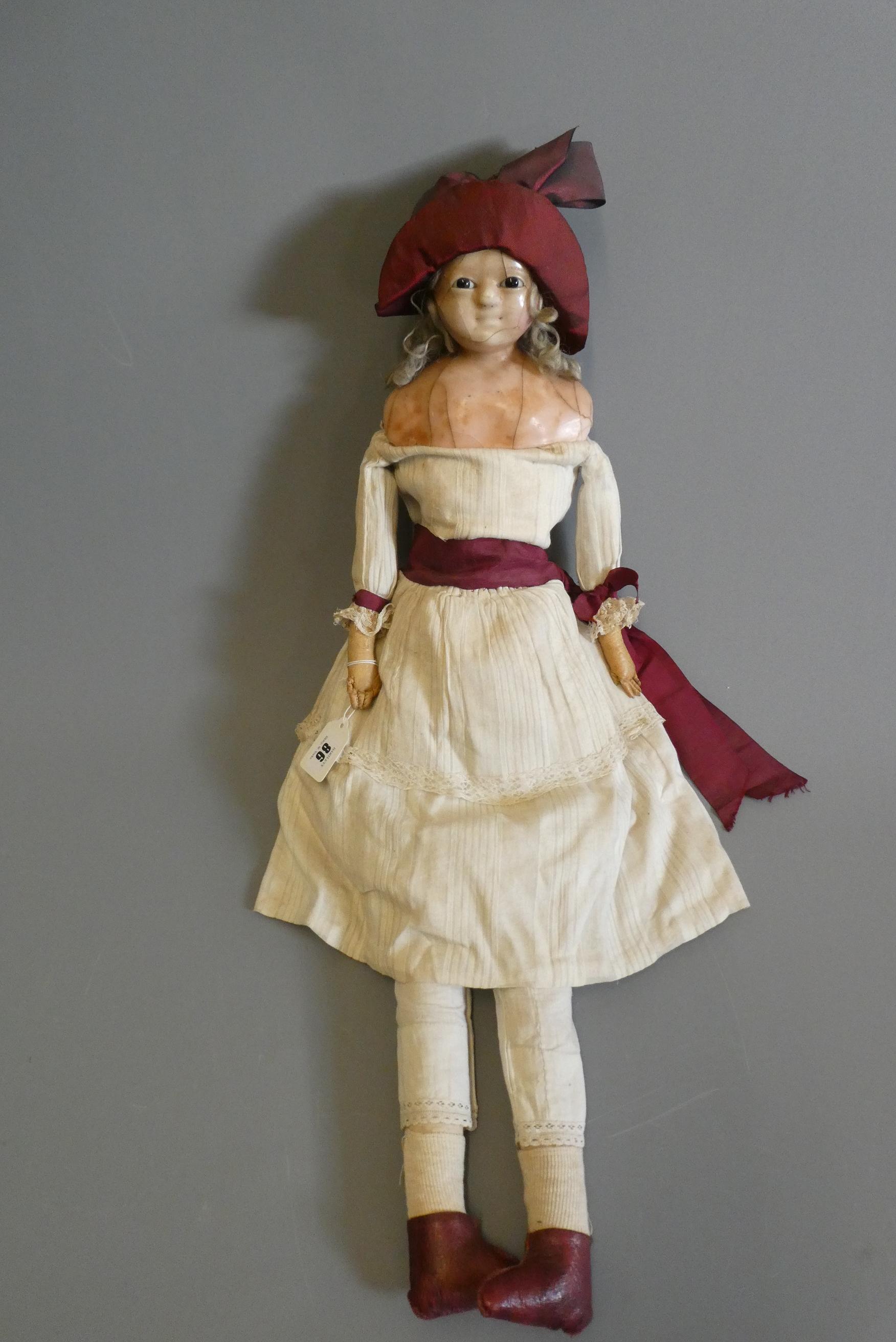 A Victorian wax shoulder head doll, with brown glass fixed eyes, closed mouth, blond wig, fabric Image