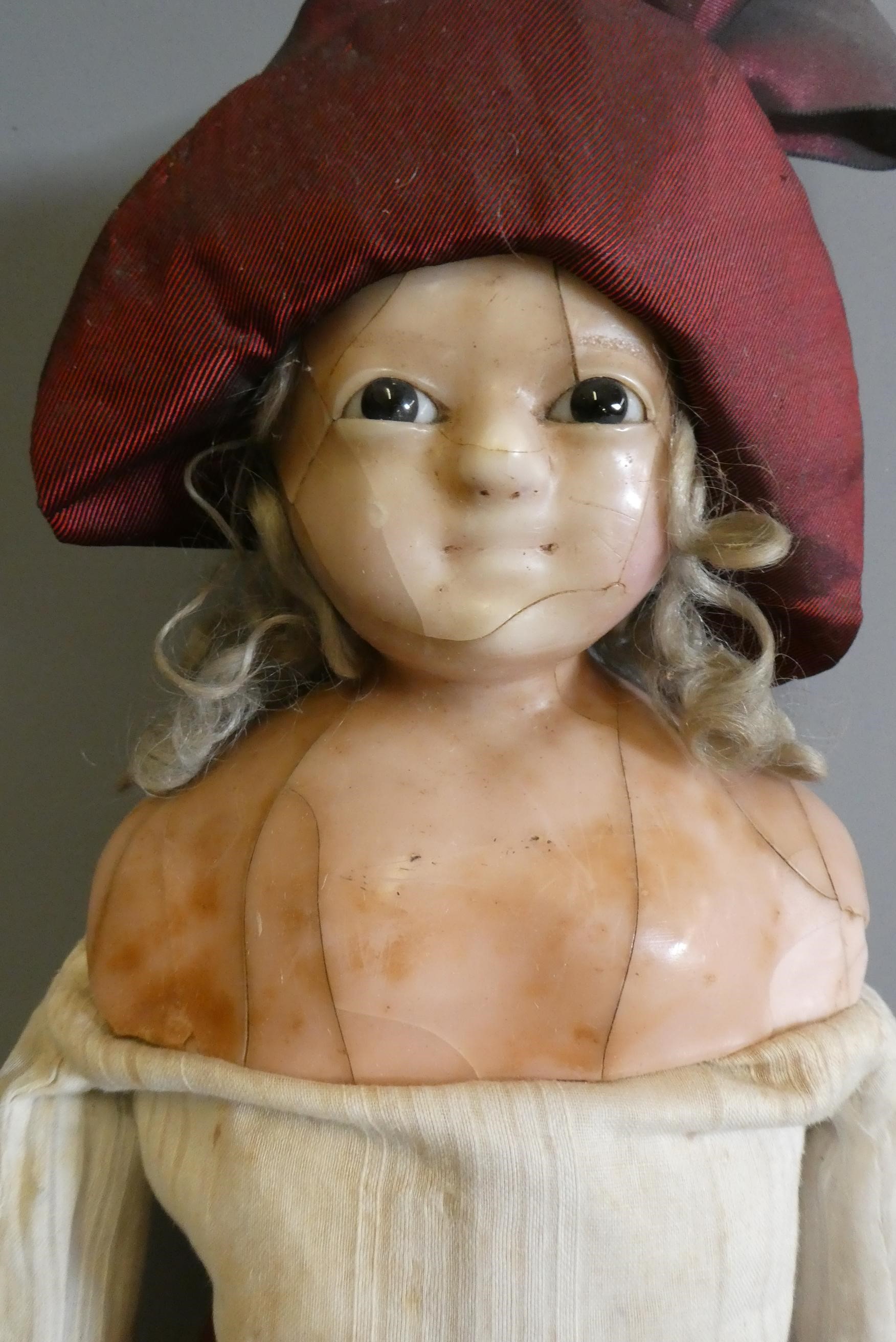 A Victorian wax shoulder head doll, with brown glass fixed eyes, closed mouth, blond wig, fabric Image