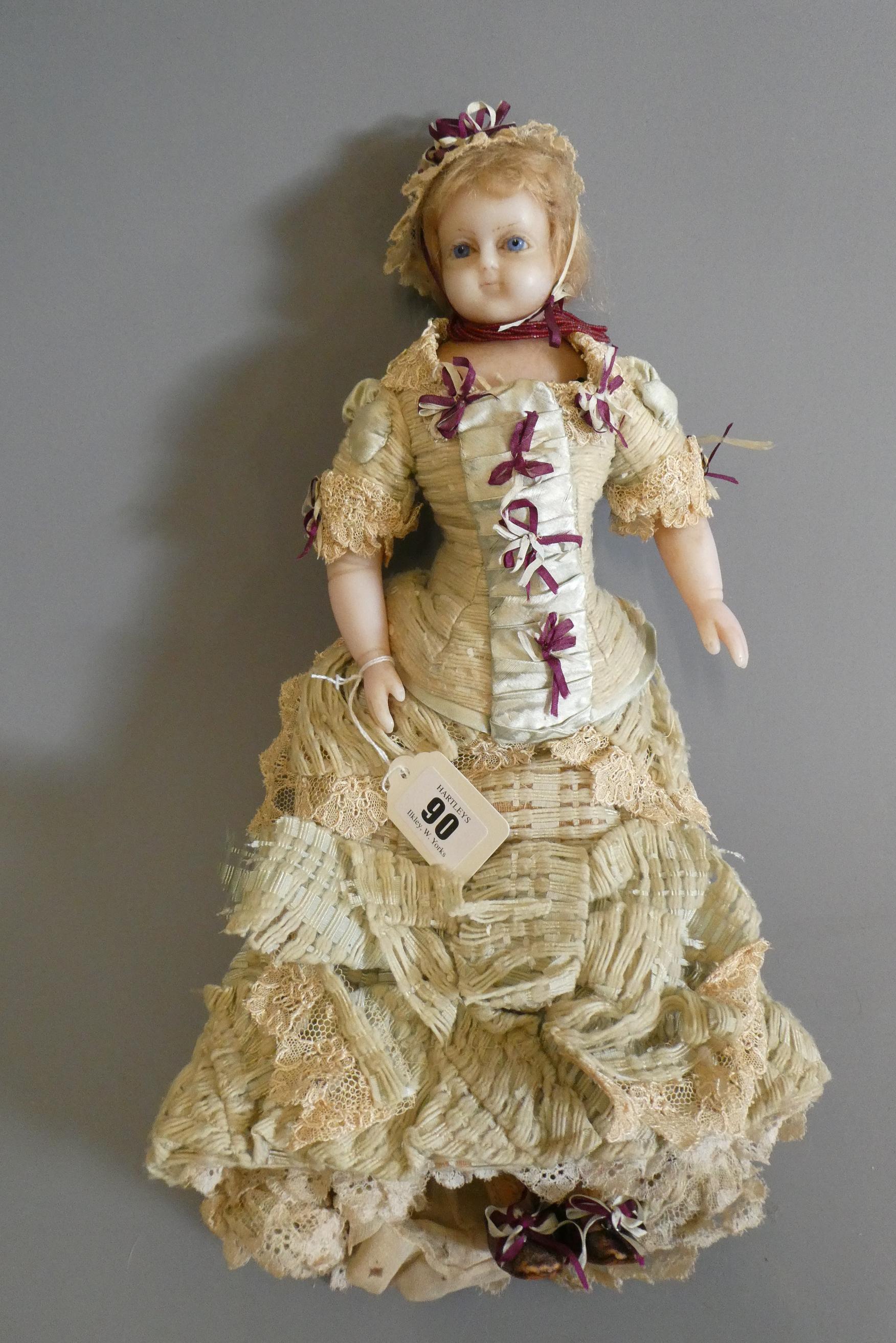 A Victorian wax shoulder head doll, with blue glass fixed eyes, closed mouth, blond wig, fabric Image