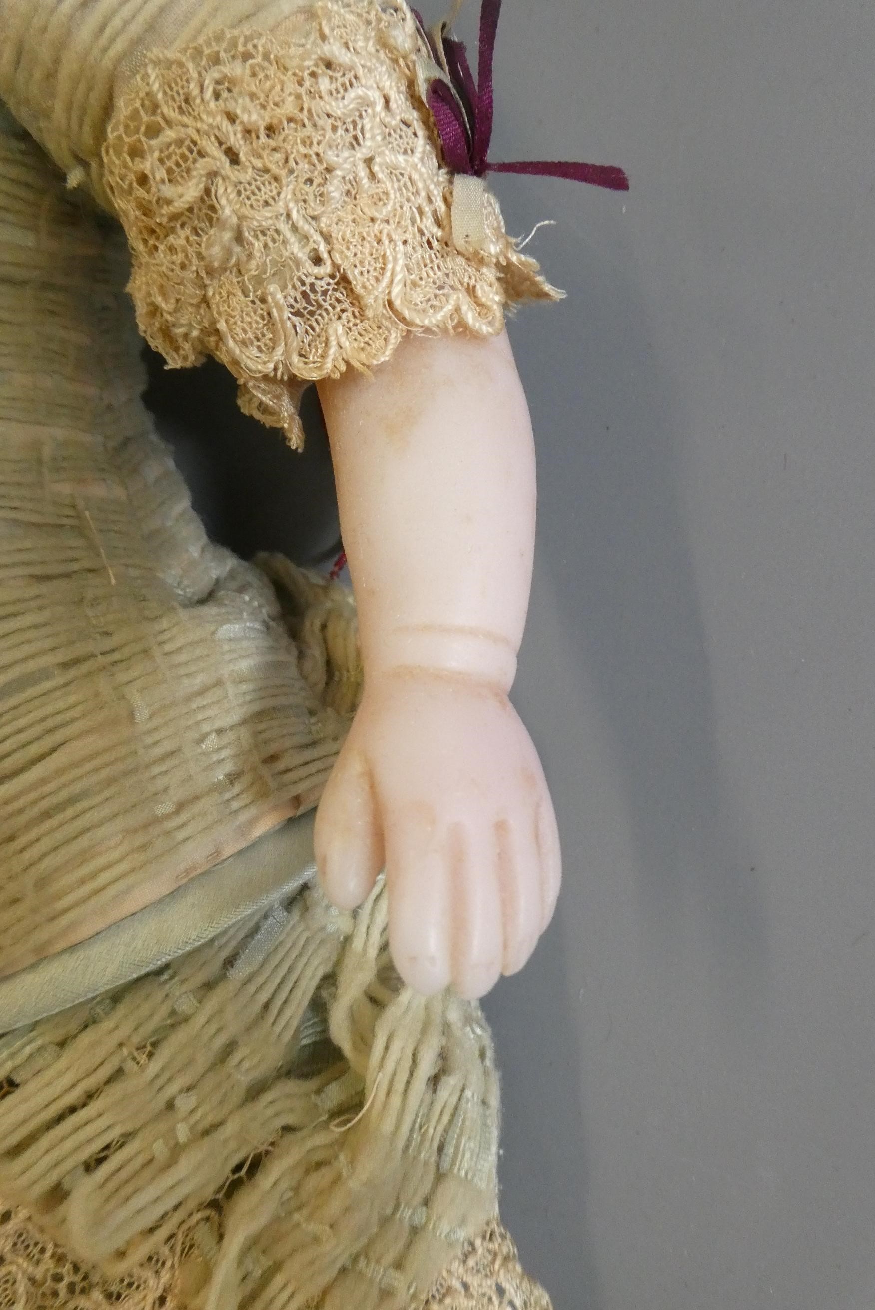 A Victorian wax shoulder head doll, with blue glass fixed eyes, closed mouth, blond wig, fabric Image