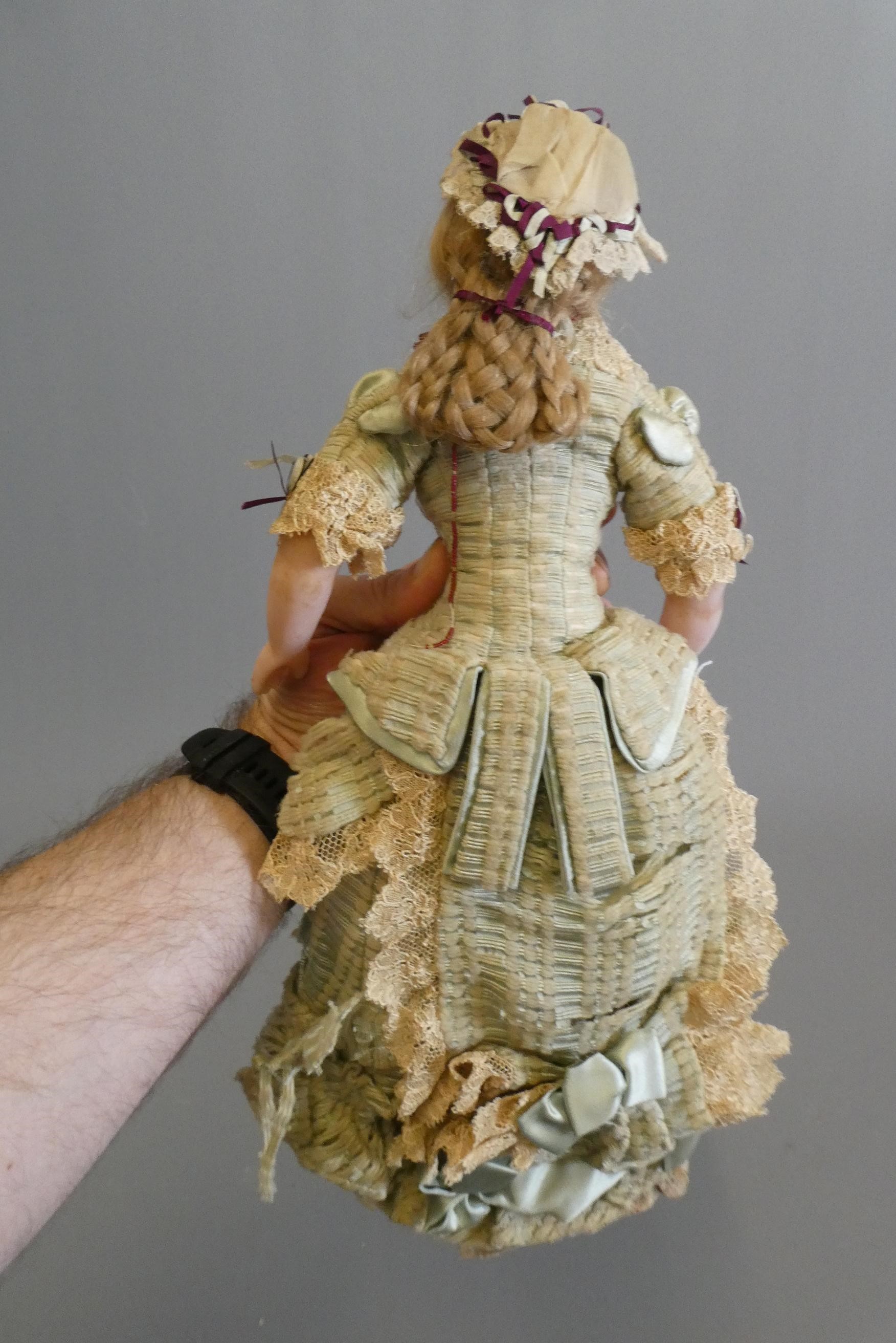 A Victorian wax shoulder head doll, with blue glass fixed eyes, closed mouth, blond wig, fabric Image