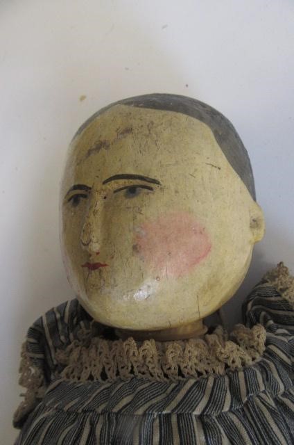 A carved and painted wooden doll Image