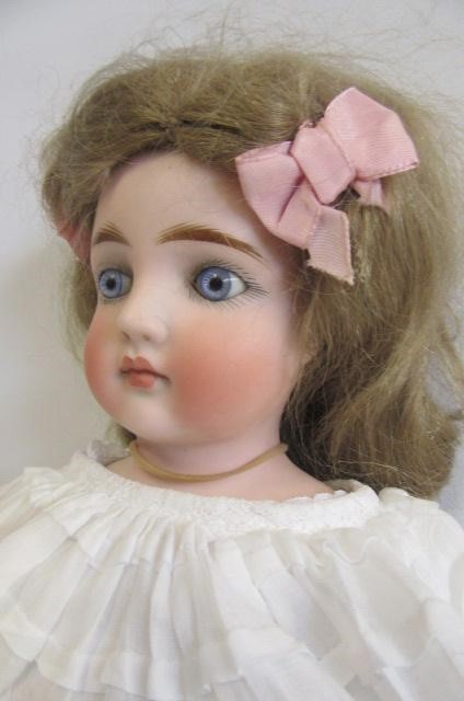 A bisque shoulder head doll with fixed blue glass eyes Image