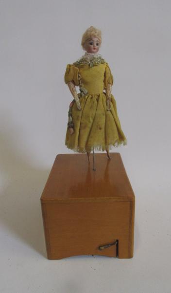 A French early 20th century dancing doll with bisque shoulder head on boxwood base with musical Image