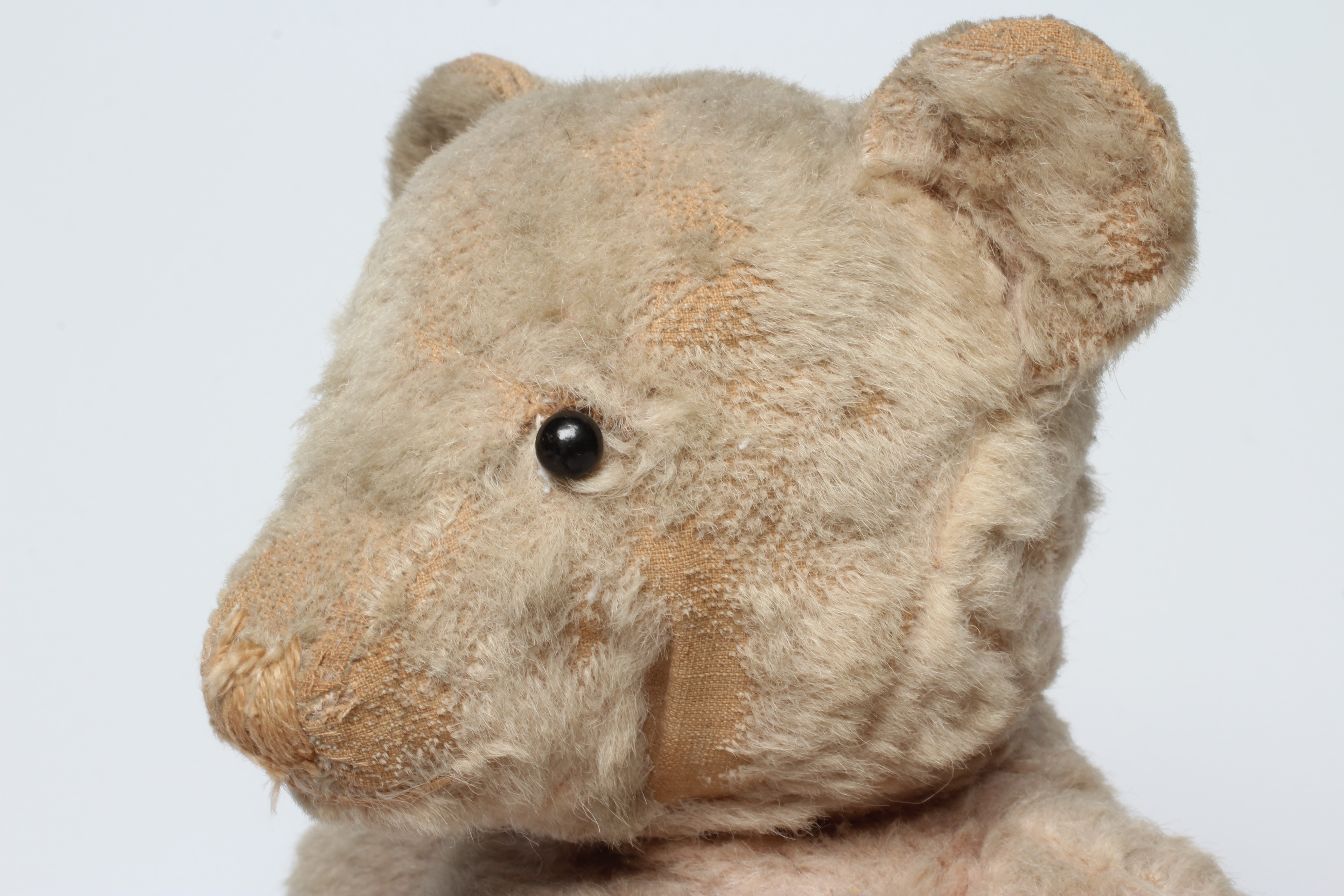 A pre-war pink jointed teddy bear, with shoe button eyes, sewn nose and cloth pads, 16" long (Est. Image