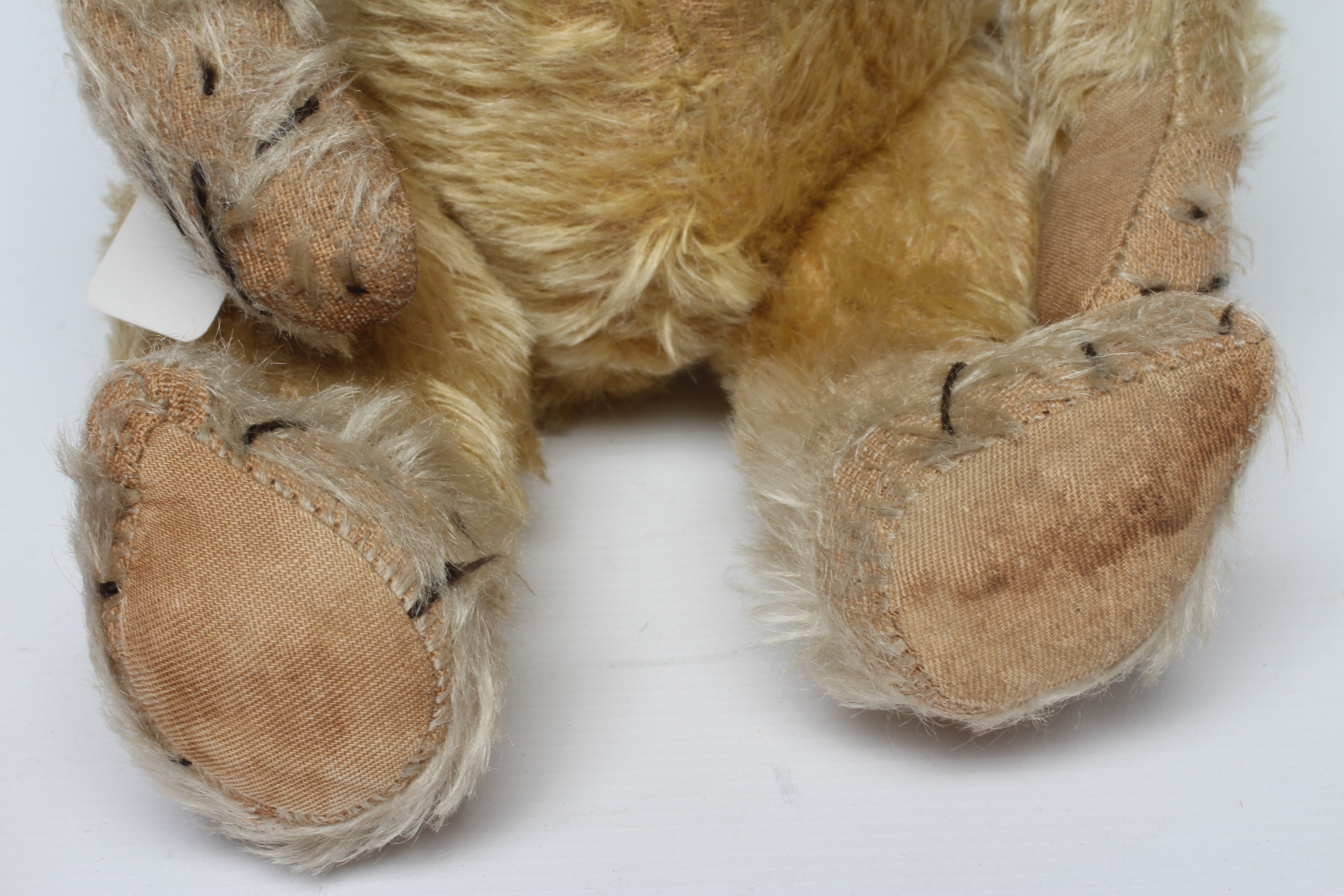 Blond mohair jointed teddy bear, c.1920, with clear glass eyes, sewn nose, large ears and cloth Image