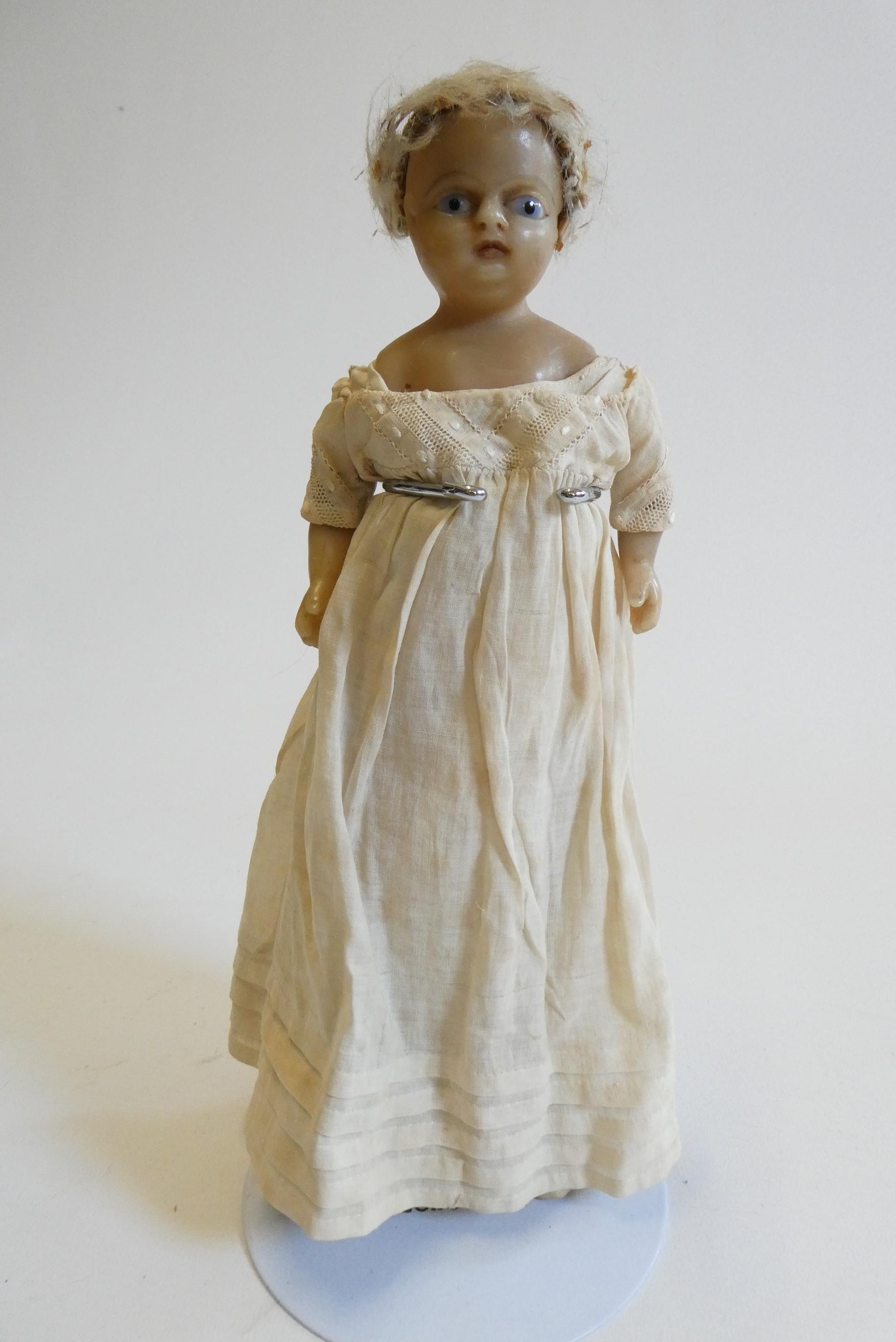A Victorian wax shoulder head doll with blue glass fixed eyes, moulded open mouth, blond wig, fabric Image