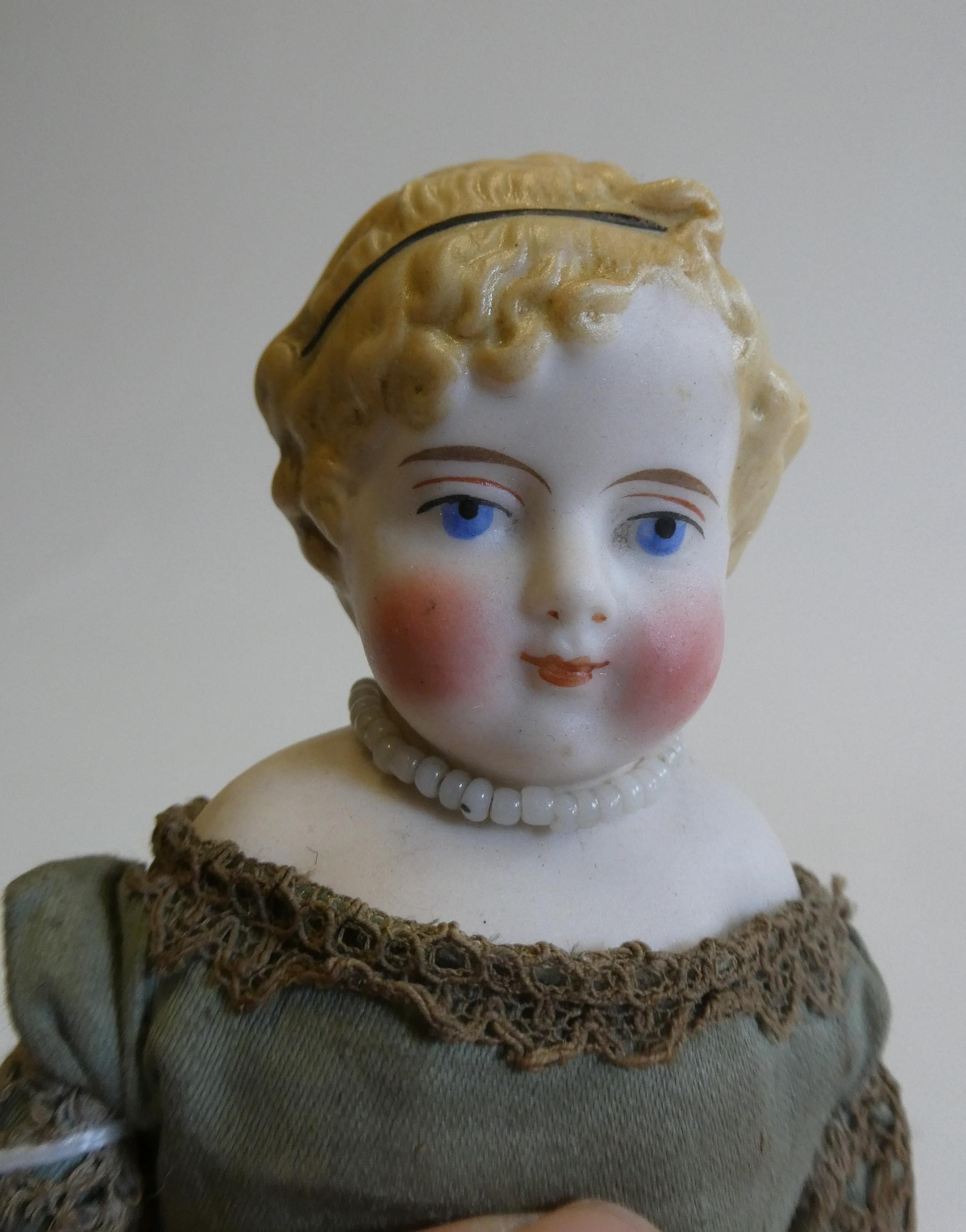 A bisque shoulder head doll, 19th century, with painted features, moulded hair, fabric body, bisque Image