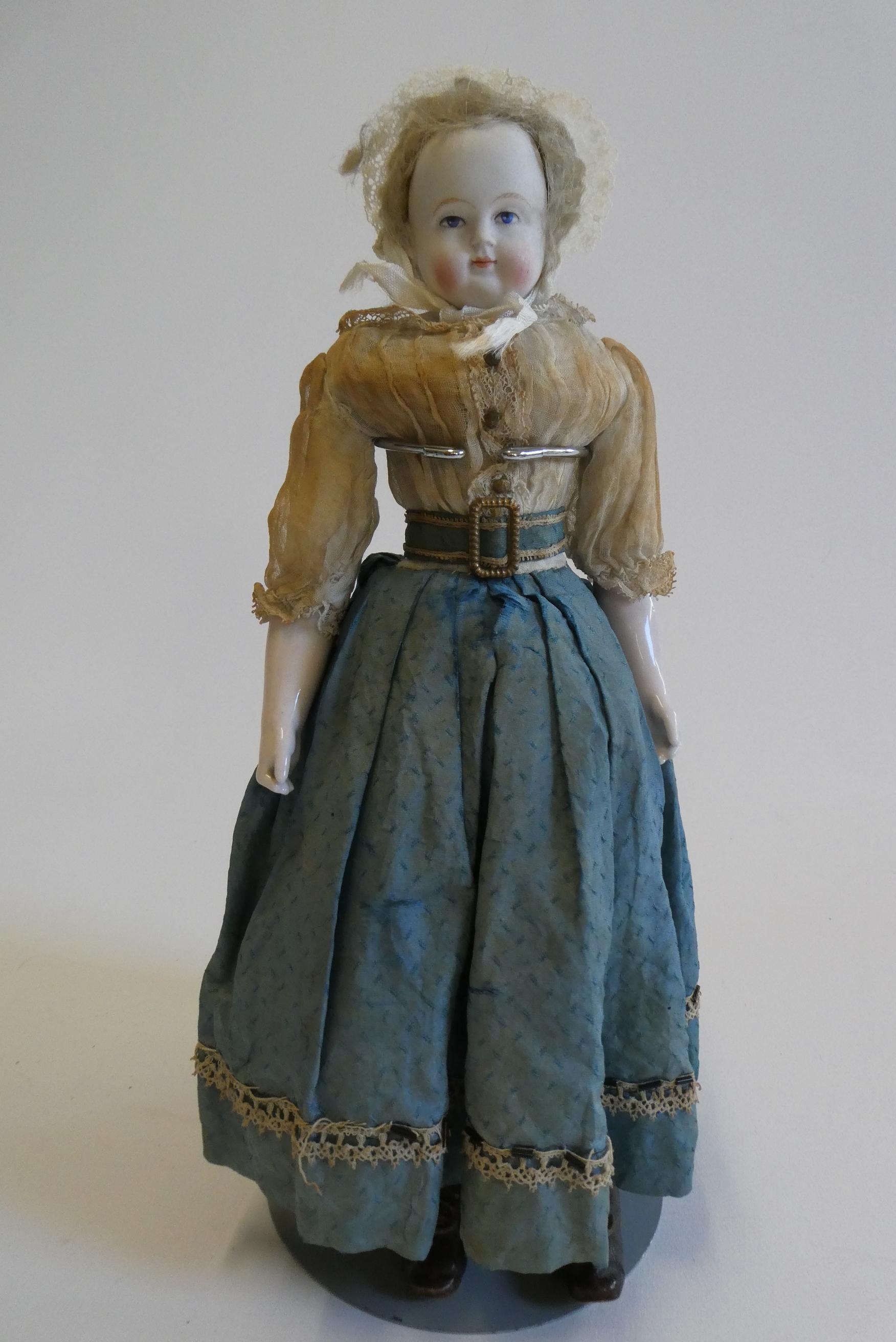 A bisque shoulder head doll, 19th century, with painted features, blond wig, fabric body and china Image