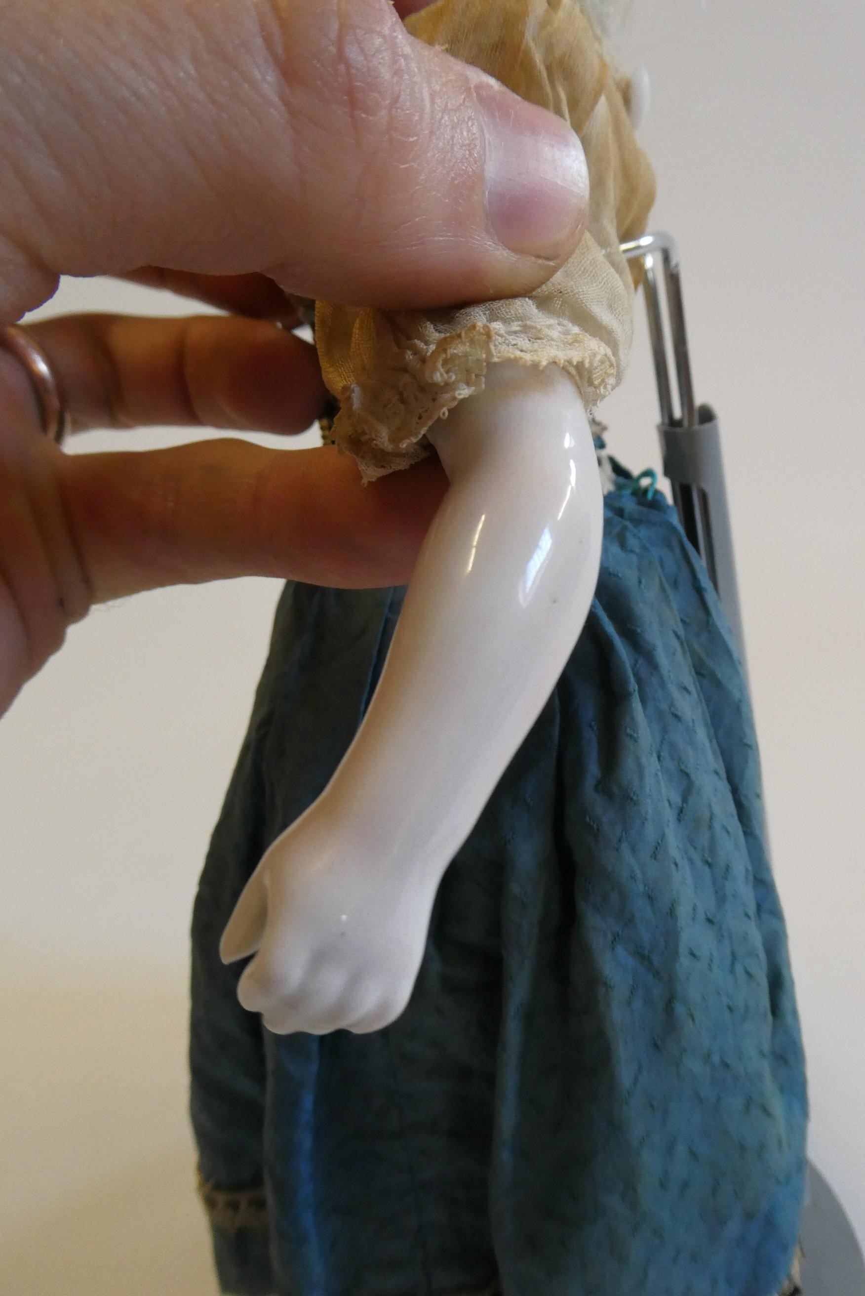 A bisque shoulder head doll, 19th century, with painted features, blond wig, fabric body and china Image