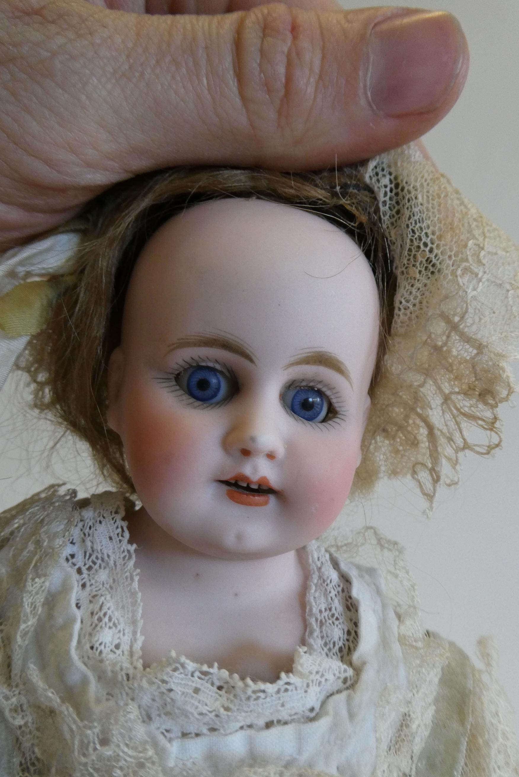 An early Armand Marseille bisque shoulder head doll with blue glass fixed eyes Image