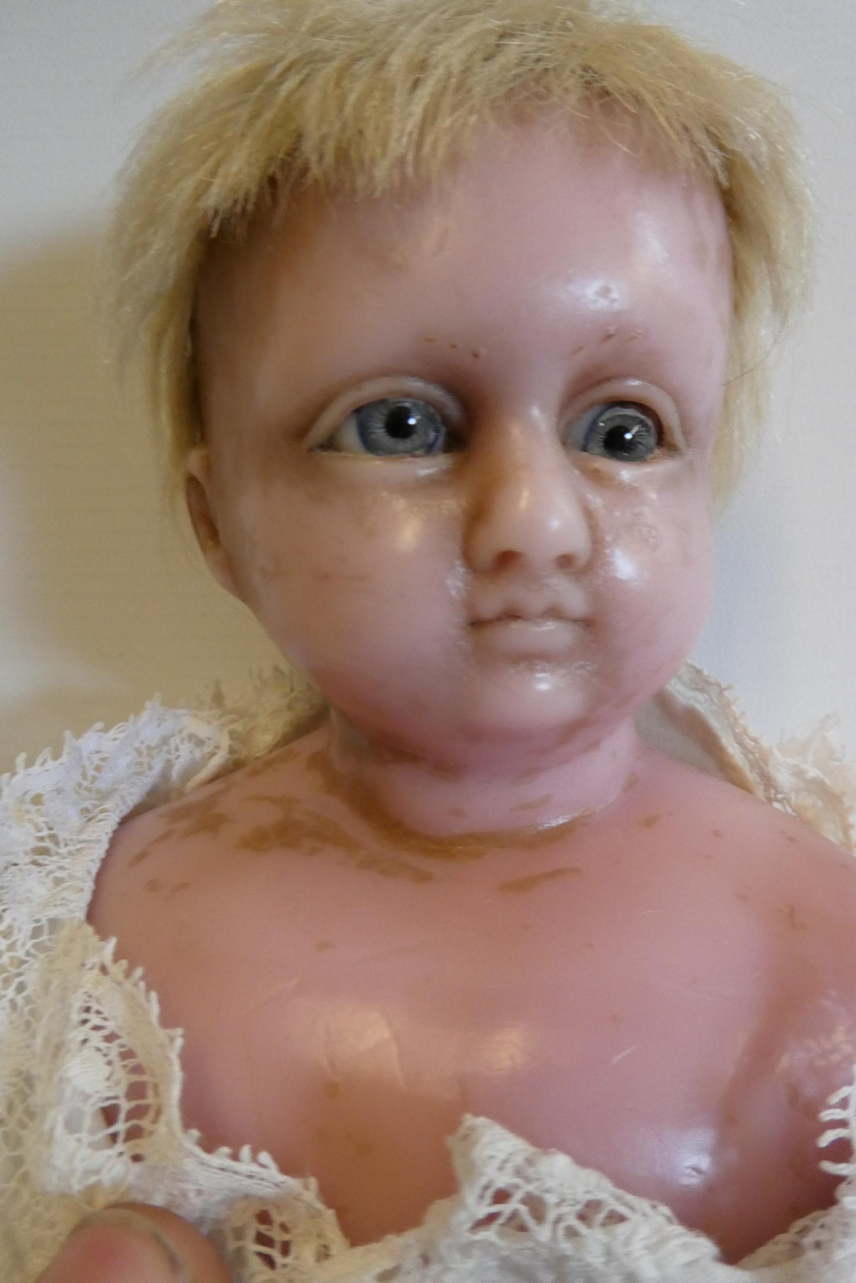 A Victorian wax shoulder head doll, with blue glass paperweight eyes, closed mouth, inserted blond Image