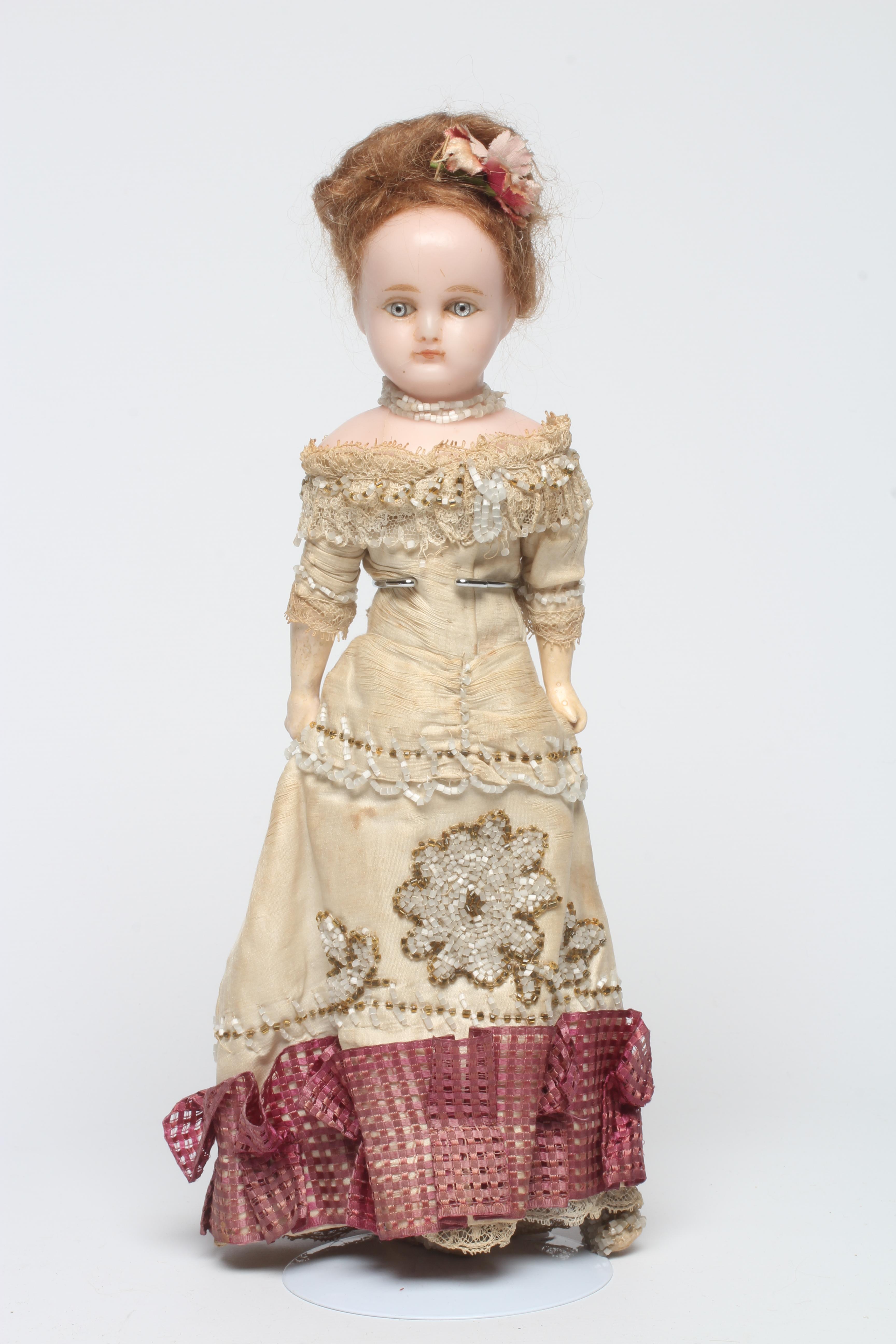 A Victorian wax shoulder head doll with blue glass paperweight fixed eyes Image