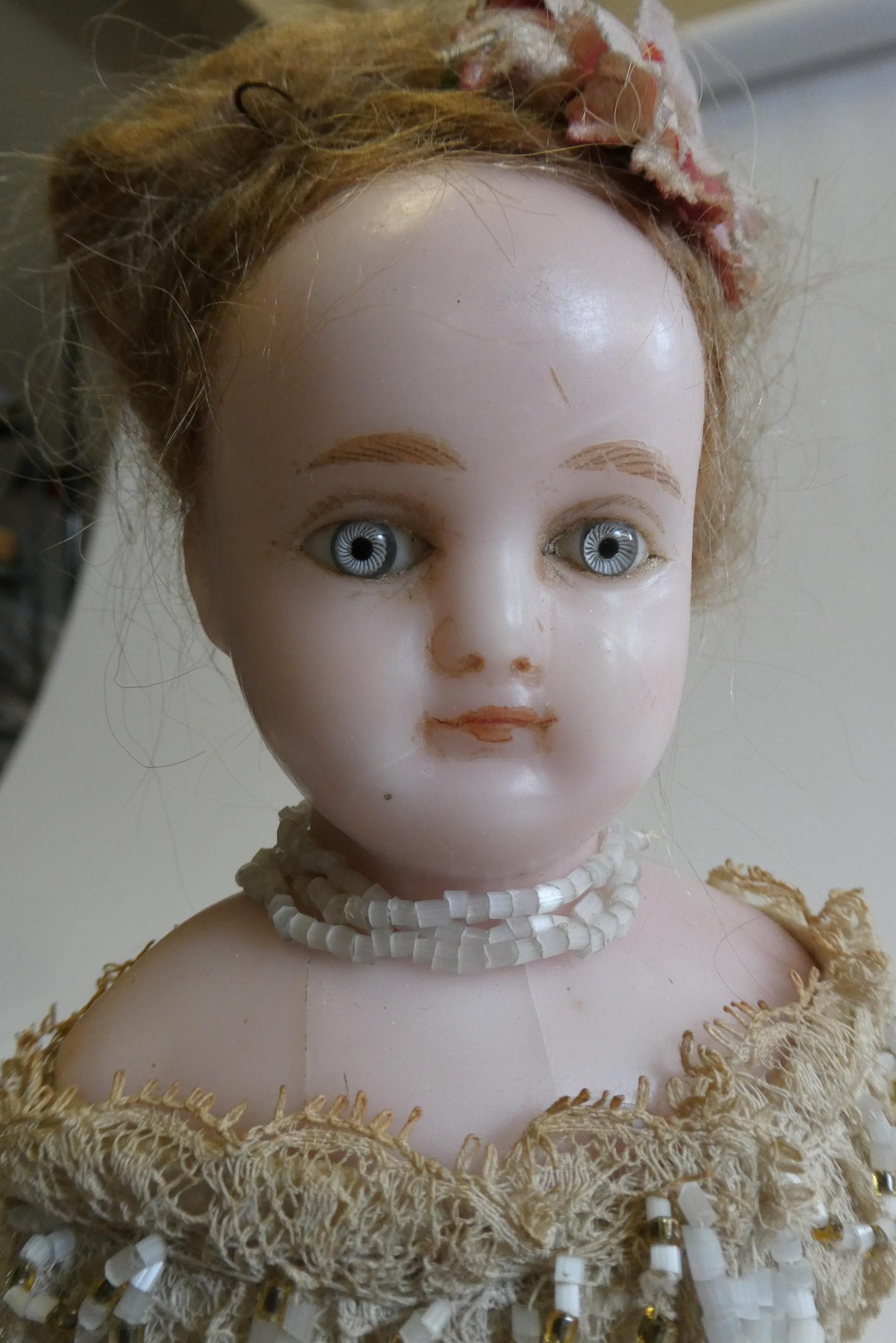 A Victorian wax shoulder head doll with blue glass paperweight fixed eyes Image