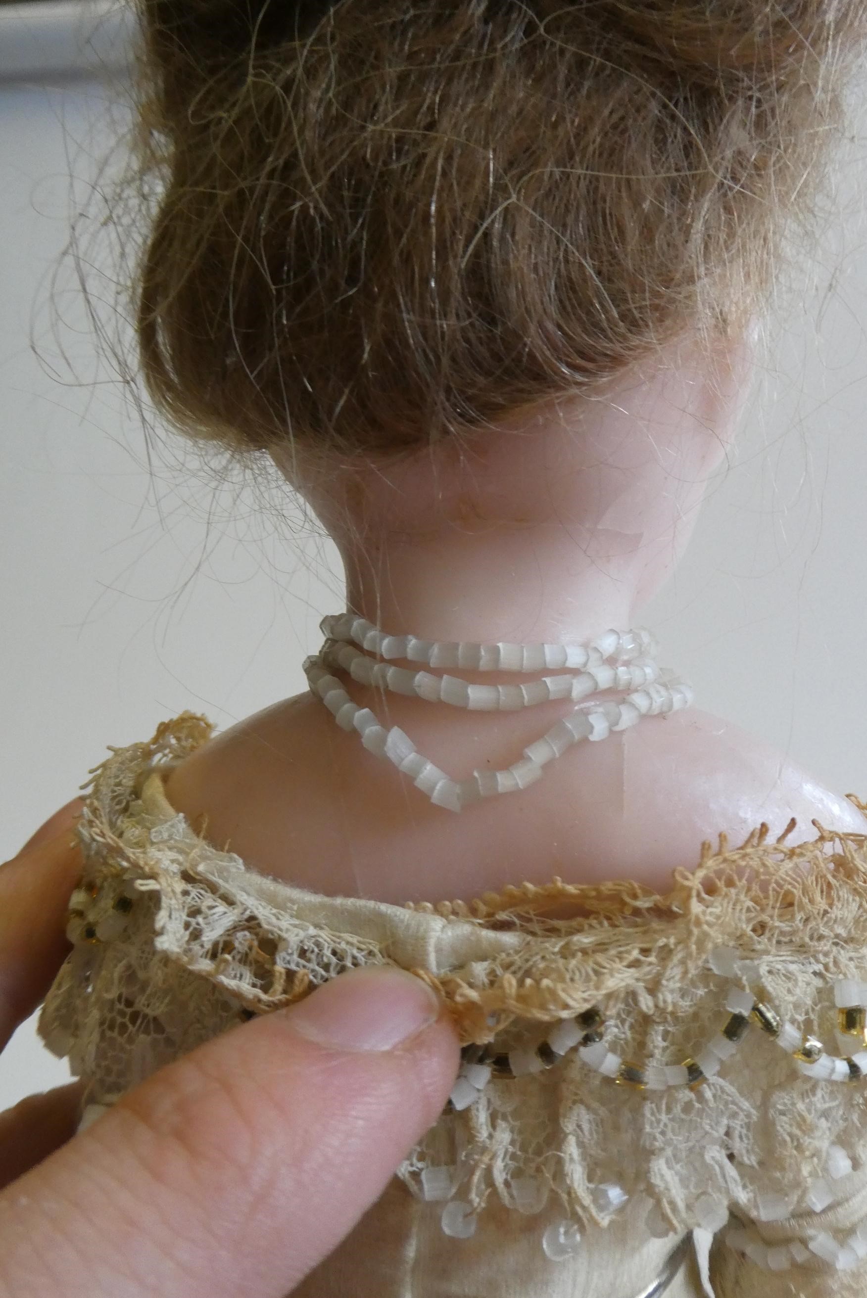 A Victorian wax shoulder head doll with blue glass paperweight fixed eyes Image