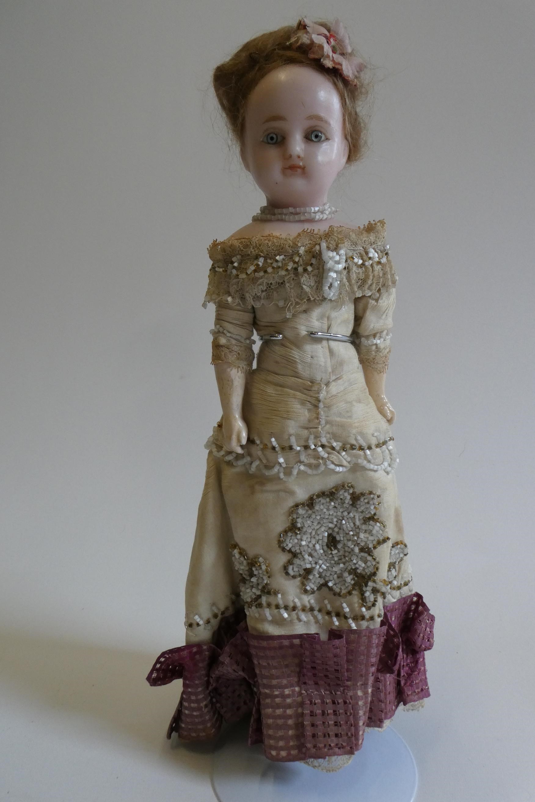 A Victorian wax shoulder head doll with blue glass paperweight fixed eyes Image
