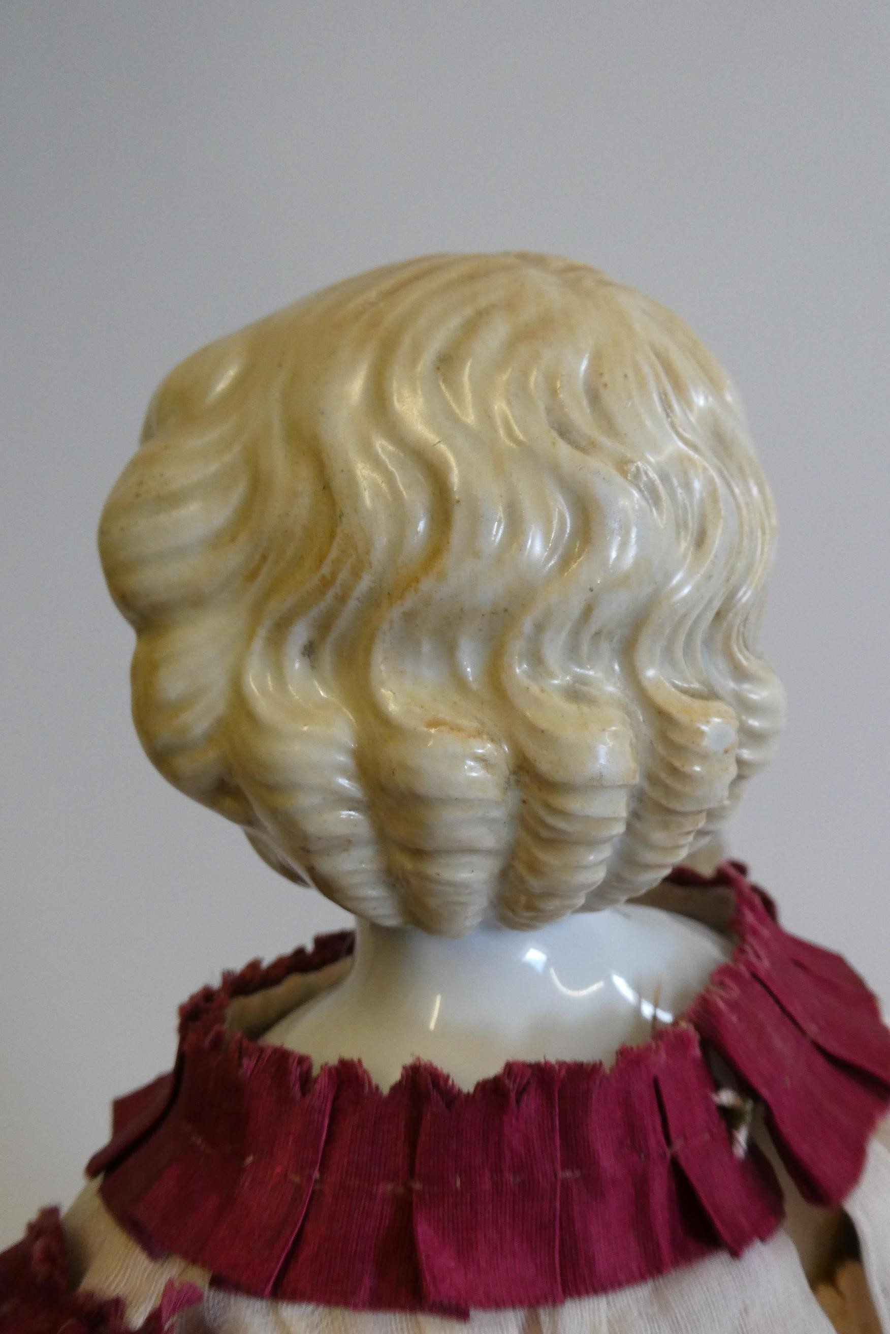 A Victorian china shoulder head doll with painted features, moulded hair, jointed kid body, lace Image