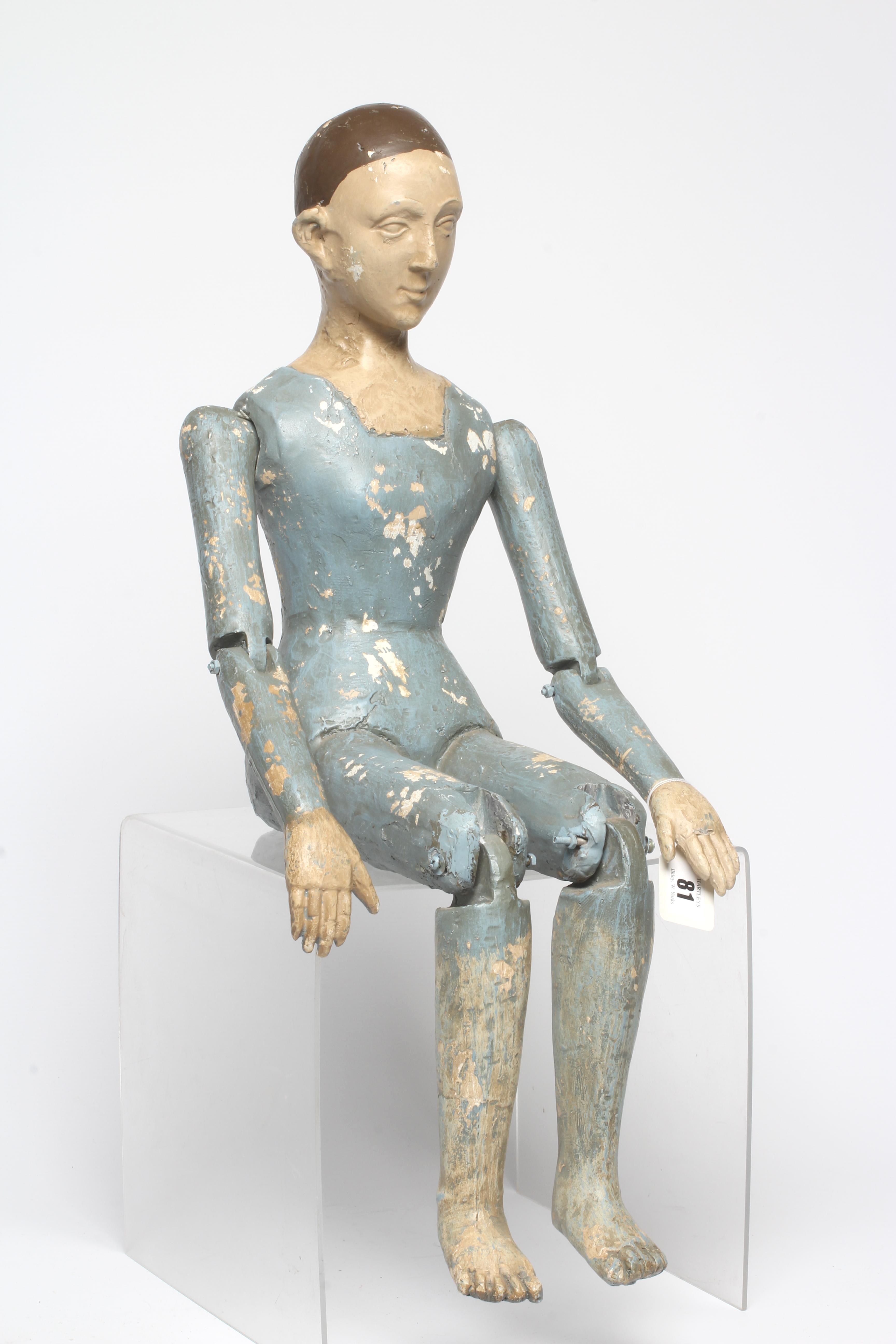 An antique seated Santos doll, of jointed wood and plaster carved construction, polychrome painted Image