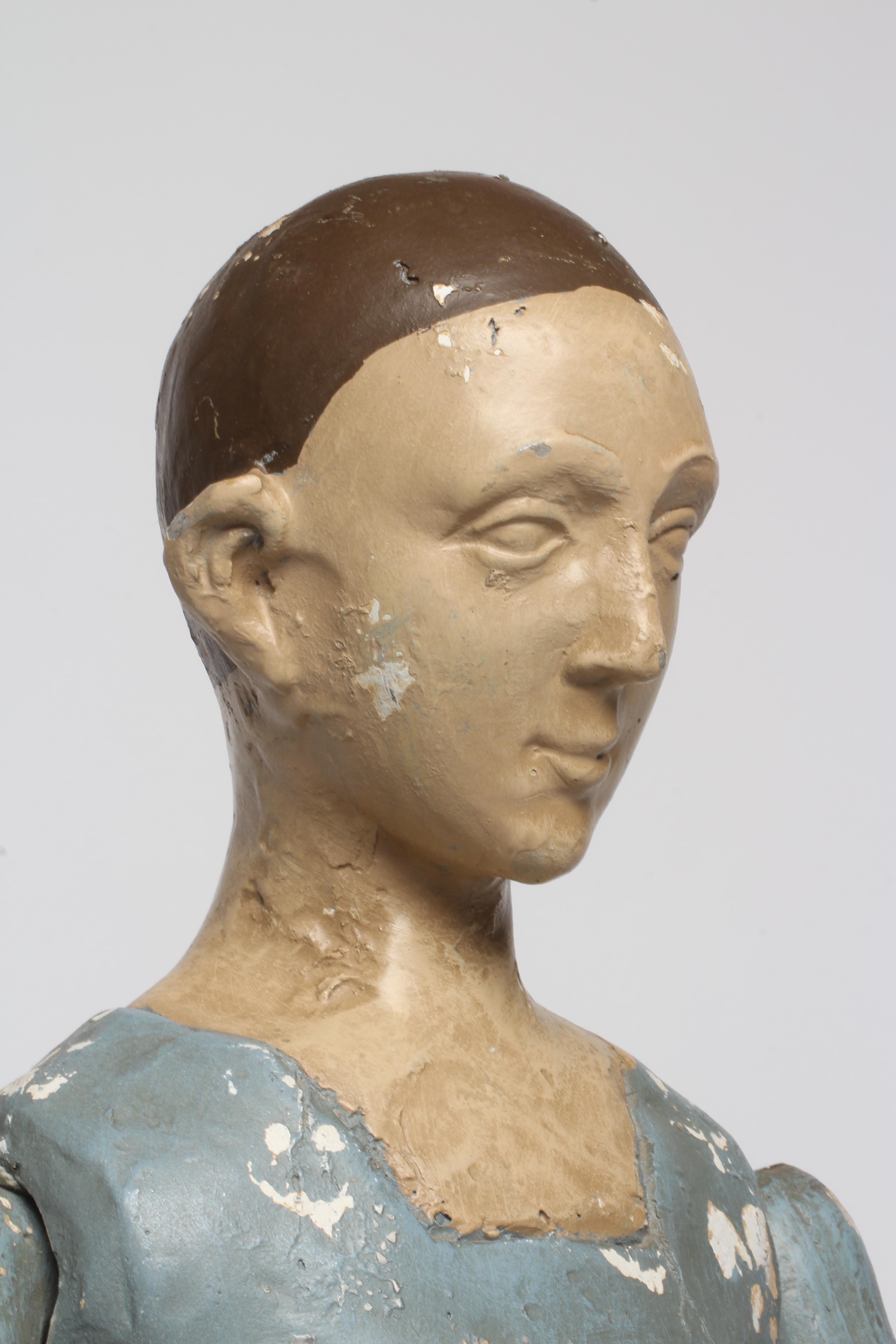 An antique seated Santos doll, of jointed wood and plaster carved construction, polychrome painted Image