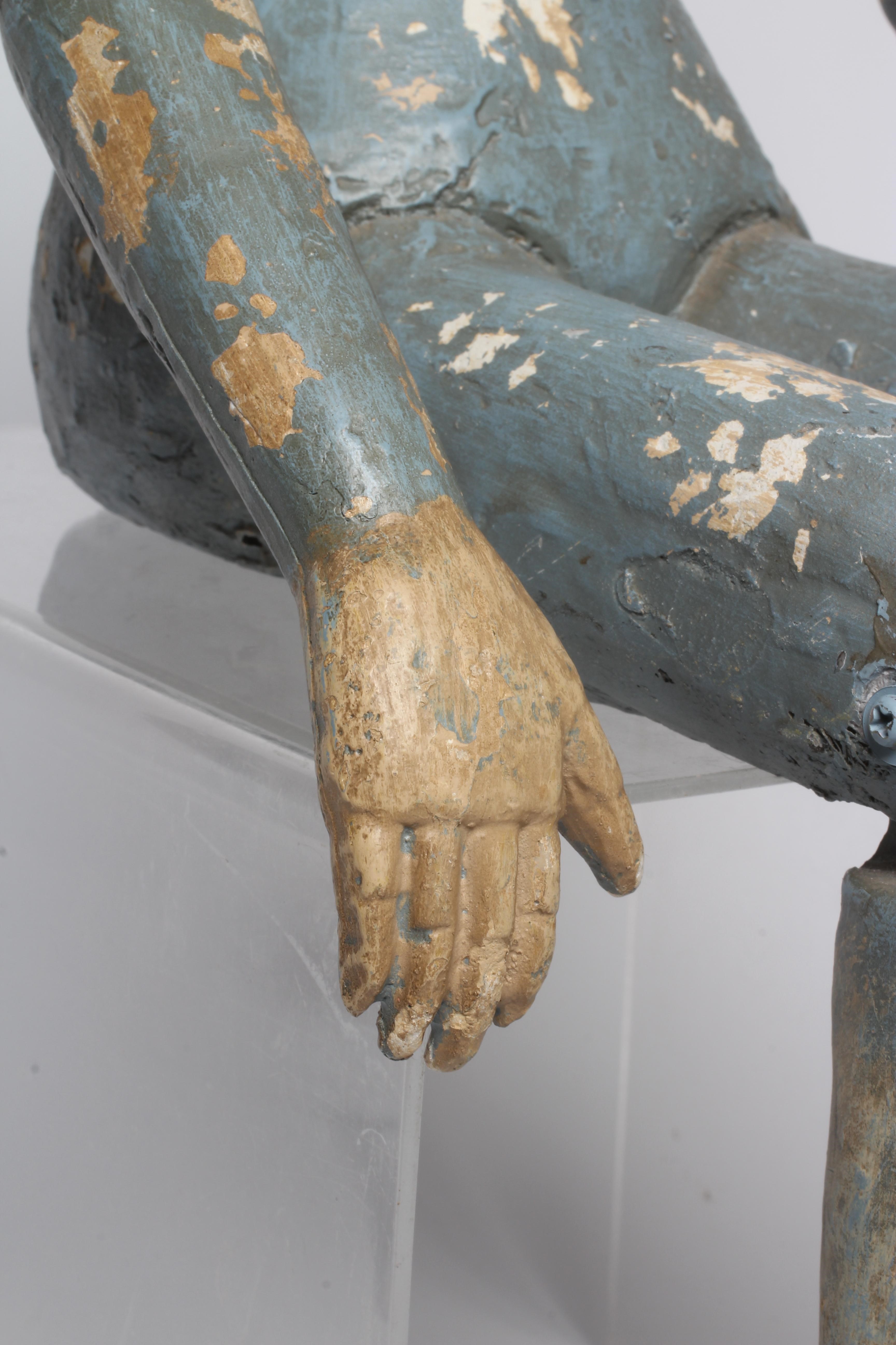 An antique seated Santos doll, of jointed wood and plaster carved construction, polychrome painted Image