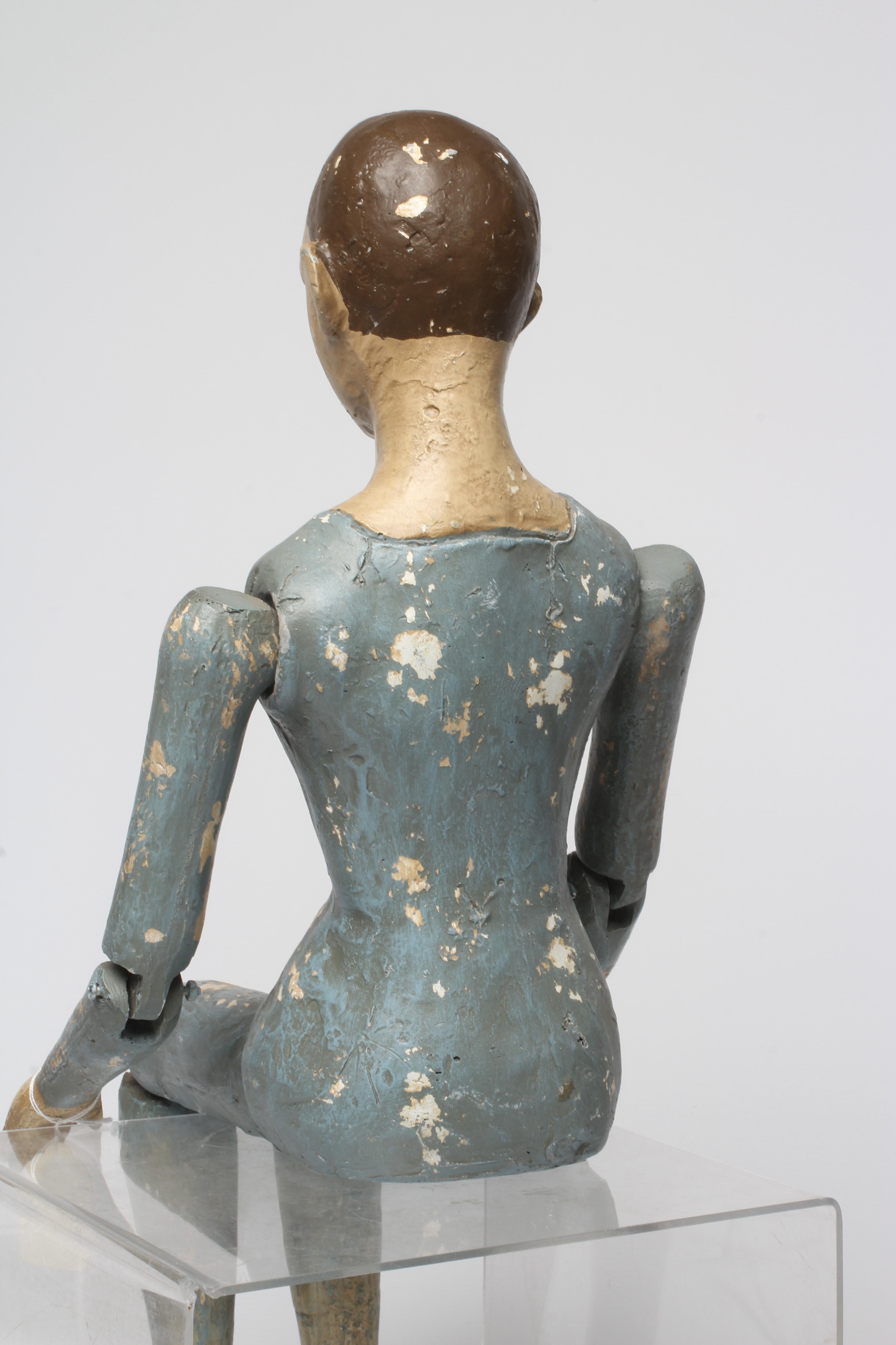 An antique seated Santos doll, of jointed wood and plaster carved construction, polychrome painted Image