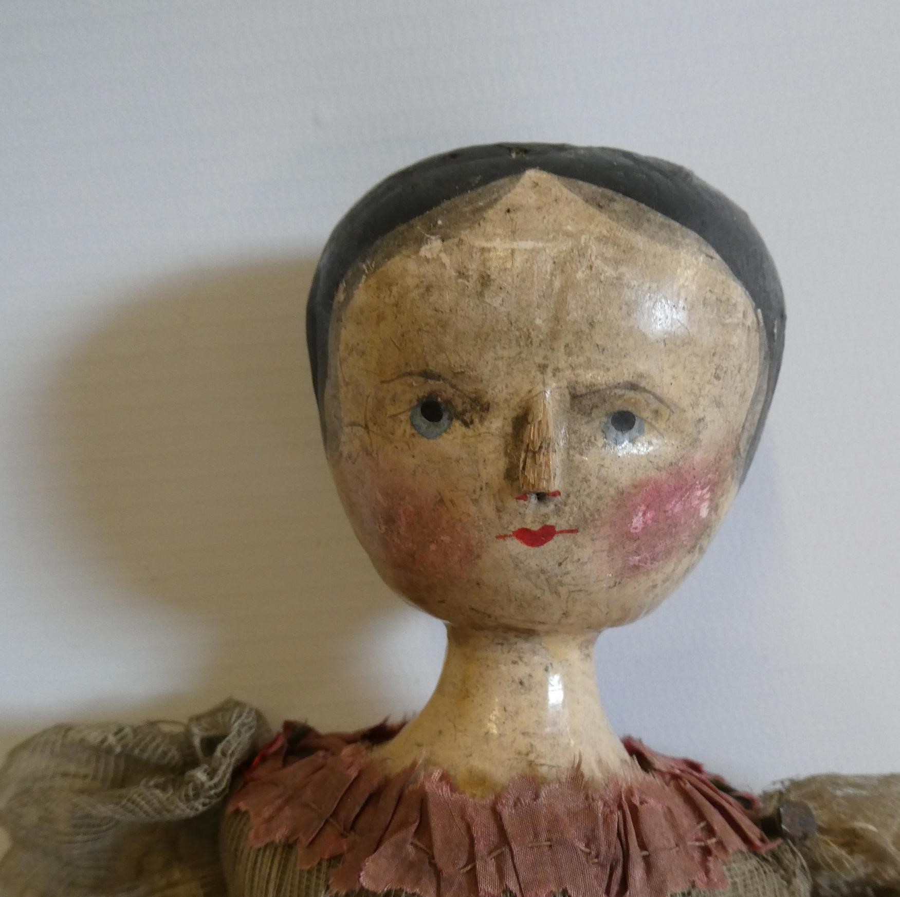 A Victorian peg doll with carved and painted head and torso, cloth upper limbs and carved wooden Image
