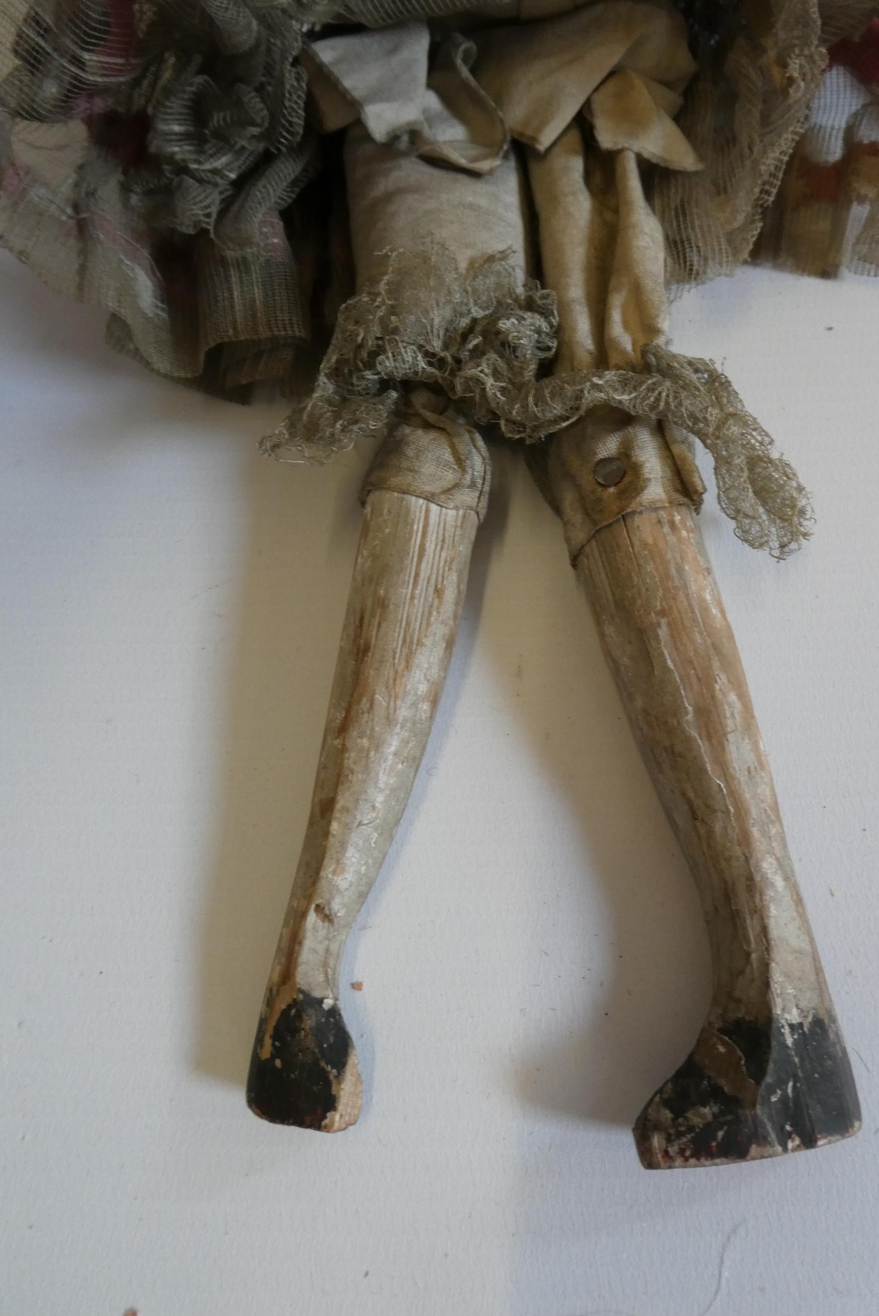 A Victorian peg doll with carved and painted head and torso, cloth upper limbs and carved wooden Image