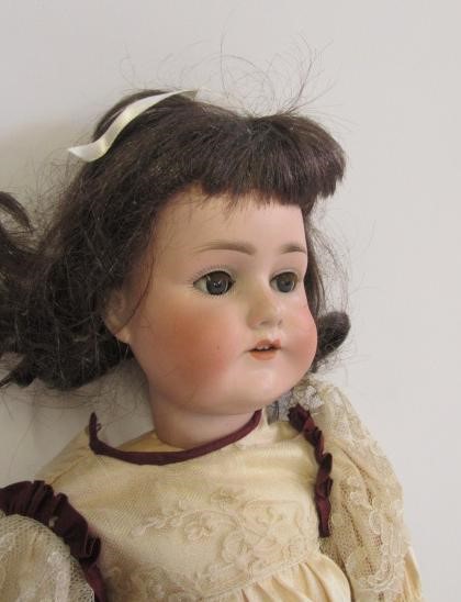 A Schoenau & Hoffmeister bisque head doll with blue glass sleeping eyes Image