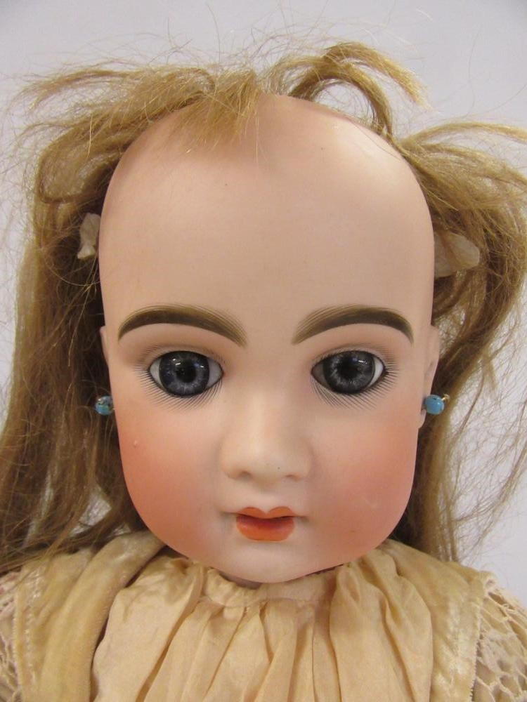 A Jumeau Bebe bisque head doll with fixed blue paperweight glass eyes Image