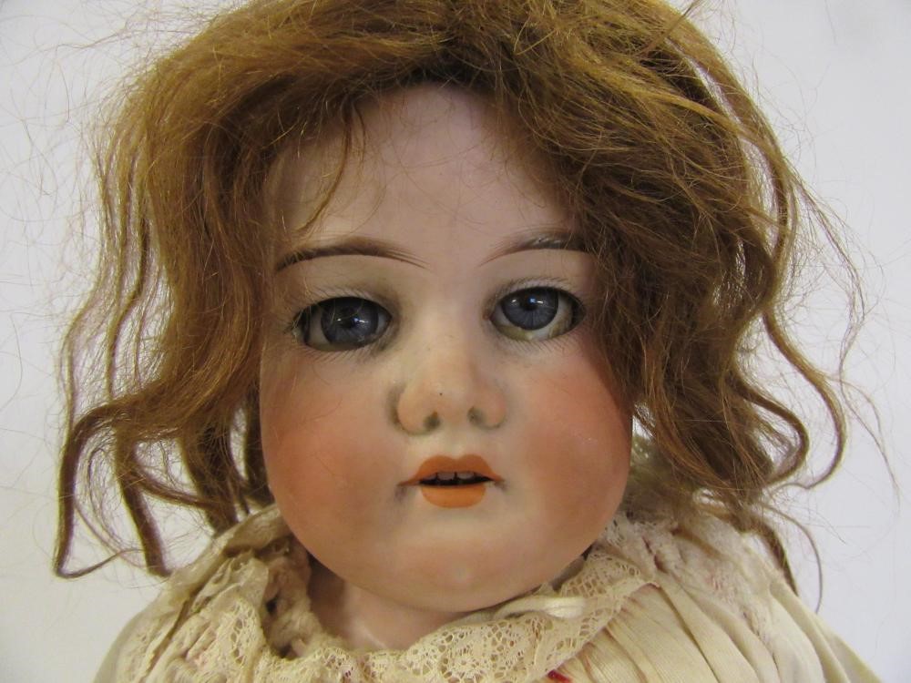 An Armand Marseille bisque shoulder head doll with blue glass sleeping eyes Image