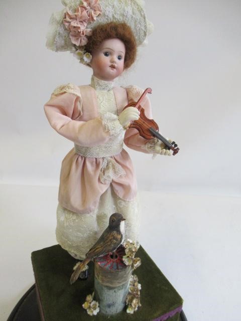 A bisque head automaton doll under dome Image