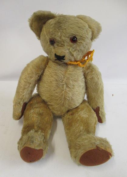 A pre-war English teddy bear, with glass amber eyes, later sewn nose, light orange plush and felt Image