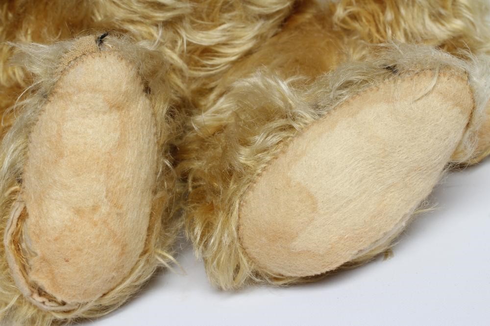 A pre-war teddy bear, with amber glass eyes, sewn nose, long orange plush and felt pads, 19 1/2" Image