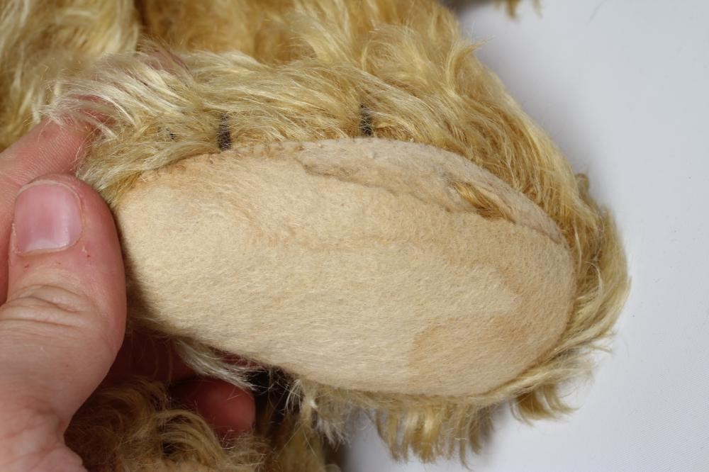 A pre-war teddy bear, with amber glass eyes, sewn nose, long orange plush and felt pads, 19 1/2" Image