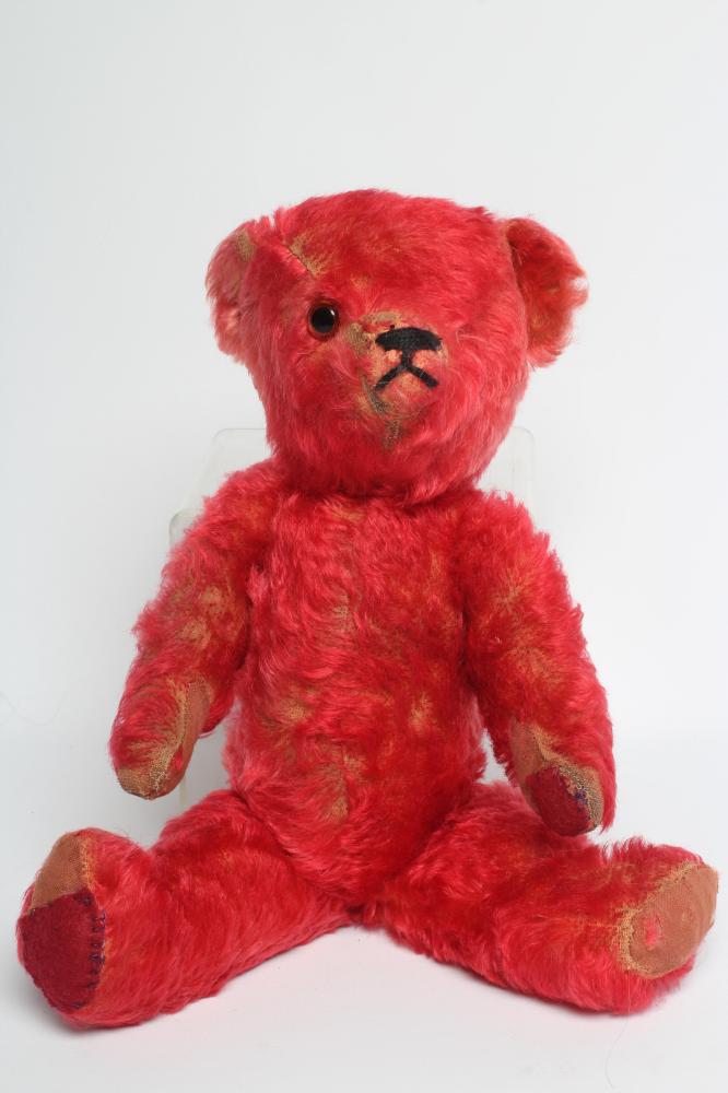 A rare pre-war red teddy bear, with one amber glass eye, sewn nose, red plush and red cloth pads, Image