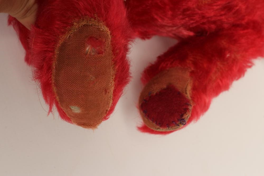 A rare pre-war red teddy bear, with one amber glass eye, sewn nose, red plush and red cloth pads, Image