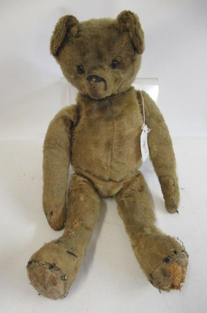 A possibly English teddy bear, c. 1915, with shoe button eyes, sewn nose, straw filled body and felt Image