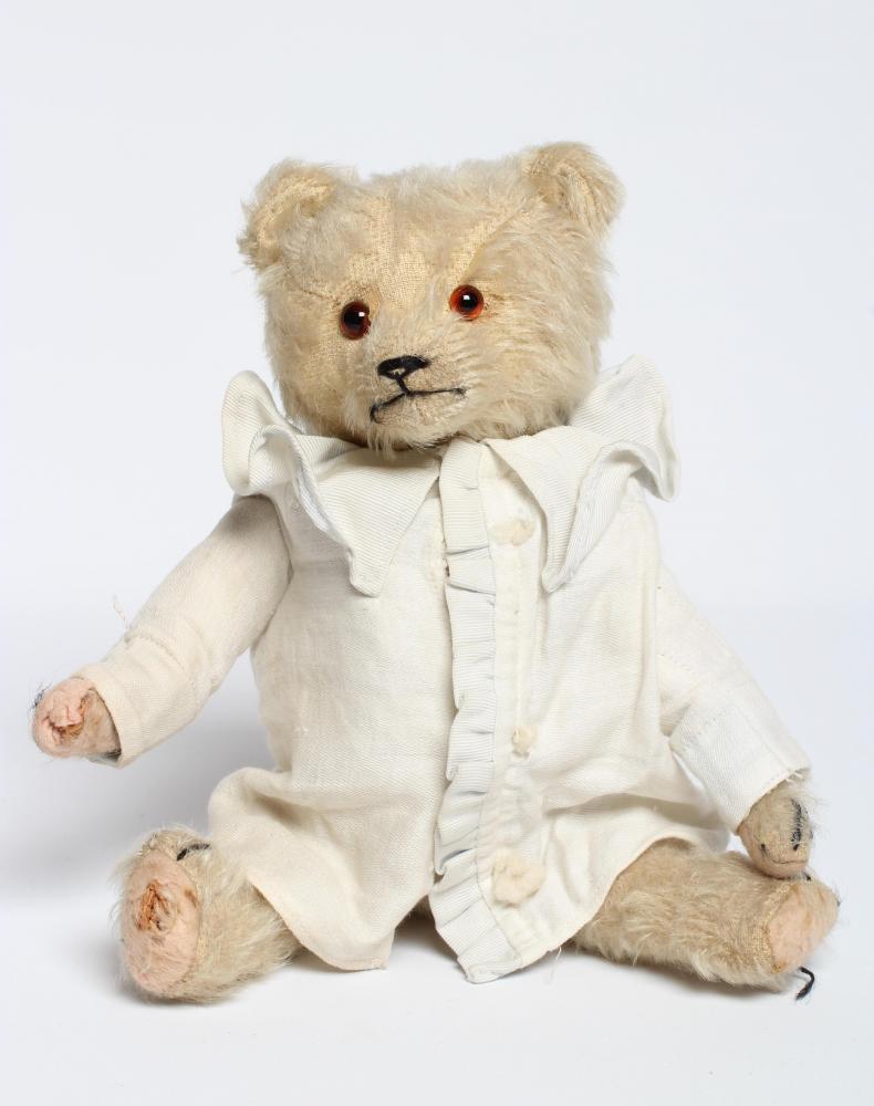 A rare pre-war white teddy bear, with amber glass eyes, sewn nose, white plush, straw filling, felt Image