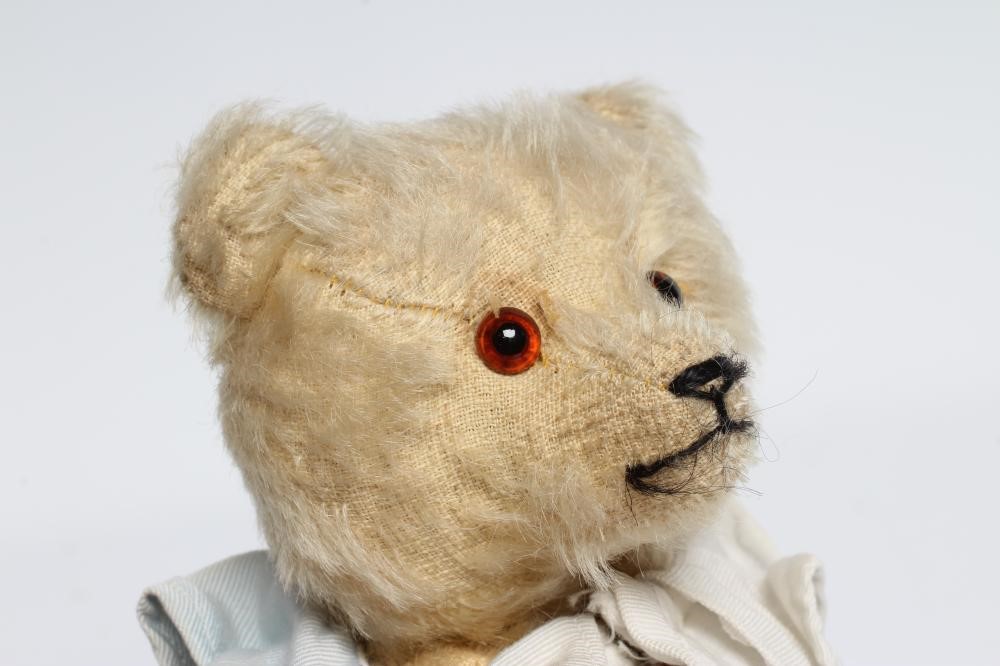 A rare pre-war white teddy bear, with amber glass eyes, sewn nose, white plush, straw filling, felt Image