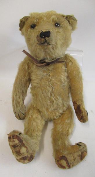 A German teddy bear, c.1910, with black shoe button eyes, sewn nose, blond plush and cloth pads, 14" Image