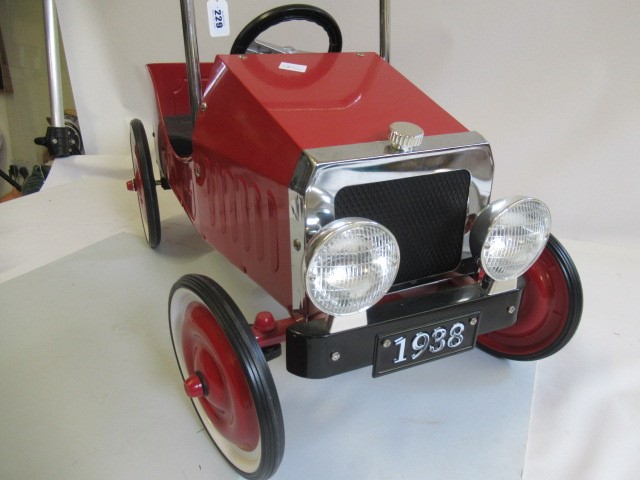A reproduction pedal car, in the 1930s style, of metal construction painted in red, with two tone Image