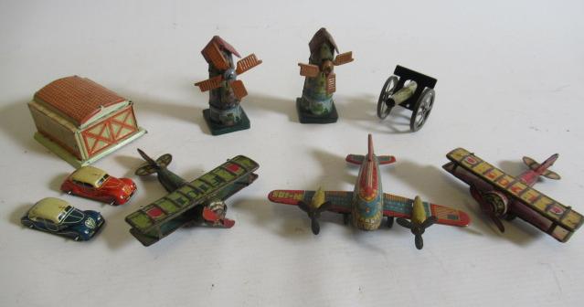 Seven German small tinplate toys comprising three aircraft, two windmills, field gun and garage with Image