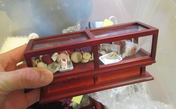 A box of dolls house furniture, including mainly wooden furniture, two dolls and a small box of shop Image
