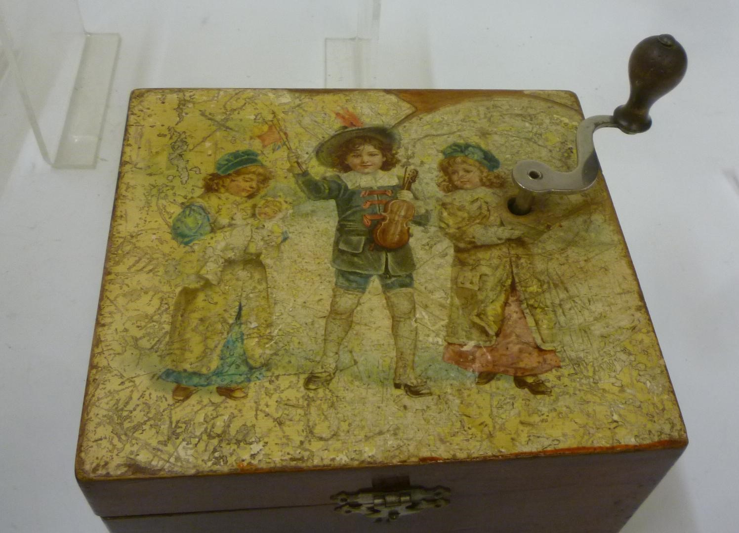 An Edelweiss disc player musical box with hand cranked movement in stained wood box with coloured Image