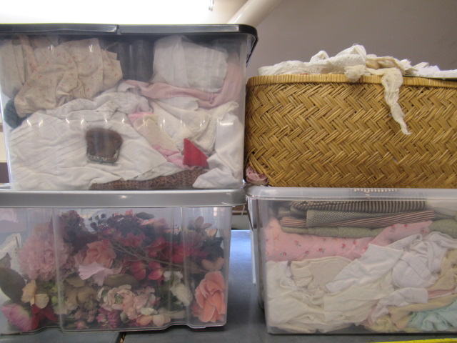Three boxes and a basket of dolls cloths Image