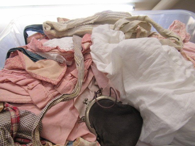 Three boxes and a basket of dolls cloths Image
