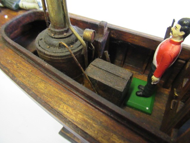 A modern wooden model of a steam launch and four lead figures with flag Image