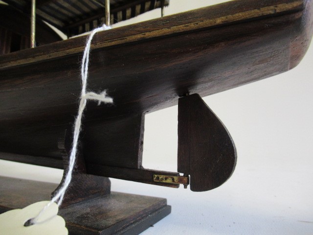 A modern wooden model of a steam launch and four lead figures with flag Image