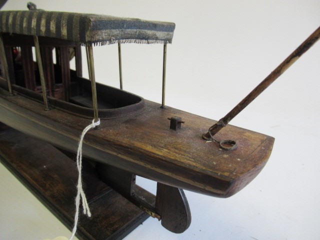 A modern wooden model of a steam launch and four lead figures with flag Image